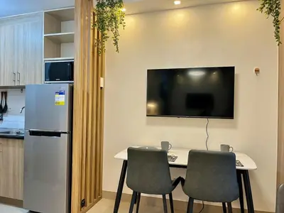 a kitchen with a table with two chairs and a tv at Liwayway Suites in Manila