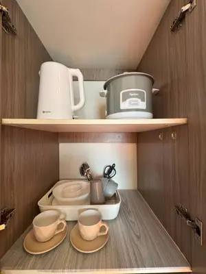 a small kitchen with two cups and cups on shelves at PaulBert's Cabins II in Sampong