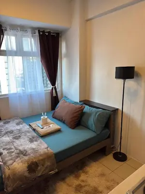 a bedroom with a bed with a lamp and a window at PaulBert's Cabins II in Sampong