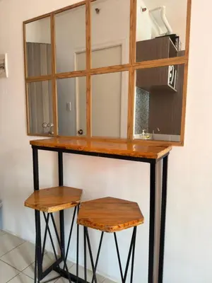 a dressing table with two stools and a mirror at PaulBert's Cabins II in Sampong