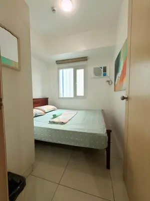 a small bedroom with a bed and a window at 2 Bedroom staycation at Jazz Residences Makati and Paid Private Parking in Manila