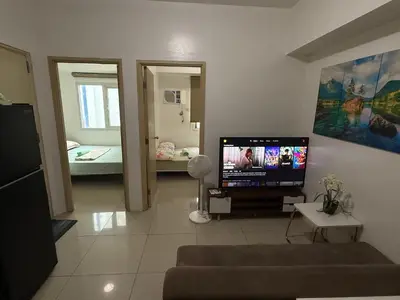a living room with a television and a room with a bed at 2 Bedroom staycation at Jazz Residences Makati and Paid Private Parking in Manila
