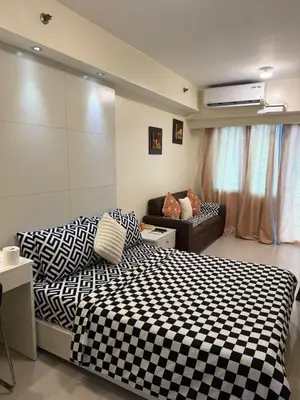 a bedroom with a black and white bed and a couch at Sea Residences Staycation Near MOA Pasay City by Rose in Manila