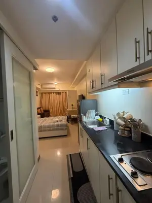 a kitchen with a counter and a room with a bed at Sea Residences Staycation Near MOA Pasay City by Rose in Manila