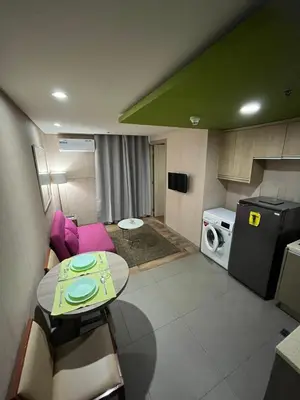 a small living room with a table and a washing machine at The Serenity Tower 90BB in Manila