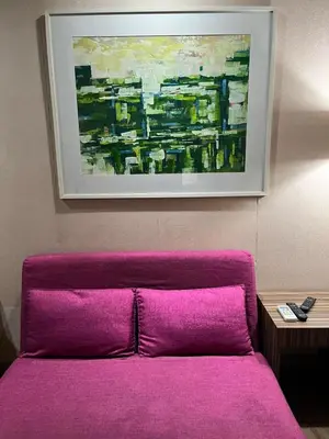 a purple couch in a room with a painting on the wall at The Serenity Tower 90BB in Manila