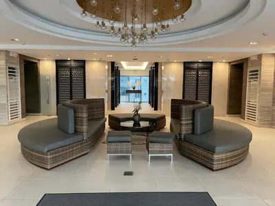 a lobby with two chairs and a table and a chandelier at FAME Residences - The 37th Suite in Manila
