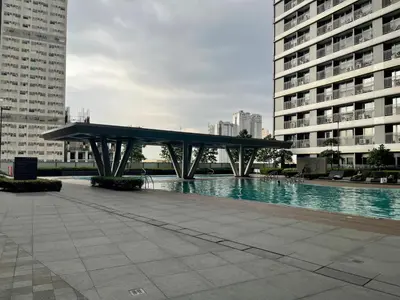 a bridge over a pool in a city with buildings at FAME Residences - The 37th Suite in Manila