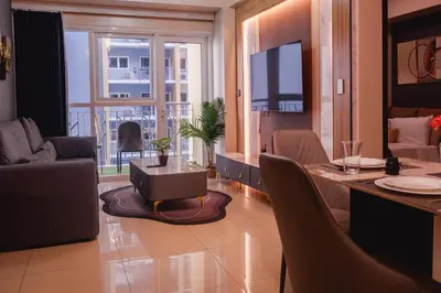 a living room with a table and chairs and a television at Luxury Condo at Bayshore Residential Phase 2 beside OKADA & near MOA in Manila