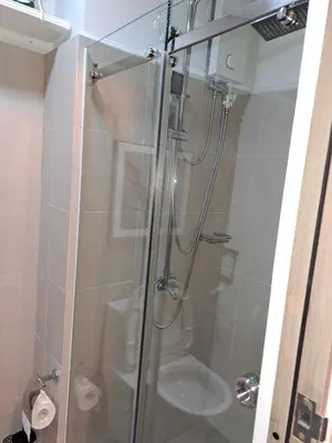 a shower with a glass door in a bathroom at Homey Roxas Blvd Condo Pool Parking WiFi in Manila