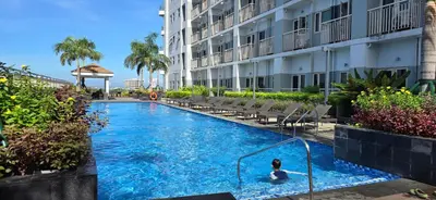a person swimming in a swimming pool next to a building at Homey Roxas Blvd Condo Pool Parking WiFi in Manila
