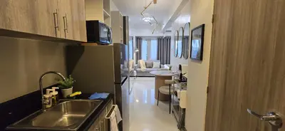 a kitchen with a sink and a living room at Homey Roxas Blvd Condo Pool Parking WiFi in Manila