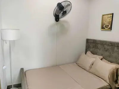 a bedroom with a bed with a fan on the wall at Gavinne Place Coast Residences in Manila