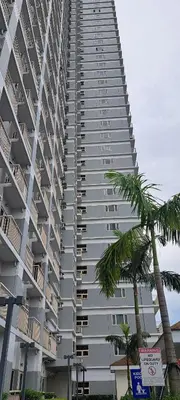 a tall building with a palm tree in front of it at Gavinne Place Coast Residences in Manila