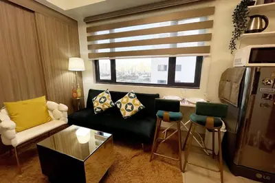 a living room with a black couch and a kitchen at Perfect Sunset View in Pasay Near MOA & NAIA in Manila