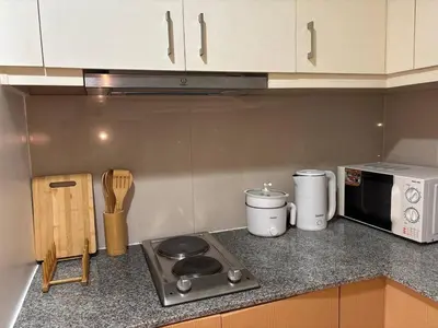 a kitchen counter with a stove and a microwave at BGC Premium 1BR with Balcony fast 600 mbps Fibre in Manila