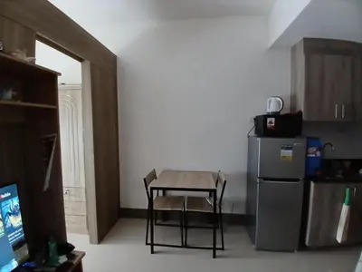 a small kitchen with a table and a refrigerator at Condo unit for rent in Manila