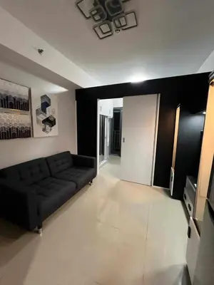 a living room with a black couch in a room at Staycation in Oasis in Manila