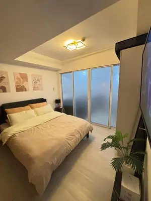 a bedroom with a bed and a flat screen tv at Staycation in Oasis in Manila