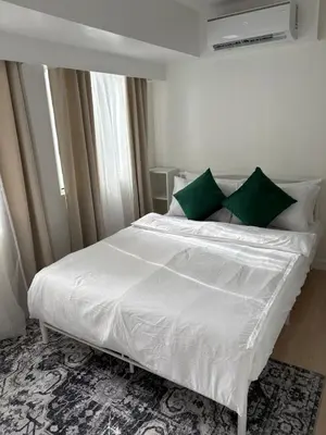 a bedroom with a large white bed with green pillows at 3BR golf view in fort victoria BGC in Manila