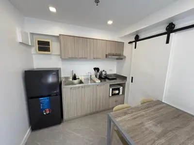 a kitchen with a black refrigerator and a table at 3BR golf view in fort victoria BGC in Manila