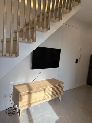 a flat screen tv sitting in a living room under stairs at 3BR golf view in fort victoria BGC in Manila