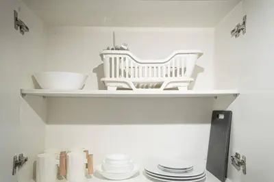a shelf with white bowls and plates on it at Boho Makati Condo w/ Wi-Fi + Workspace | Red in Manila