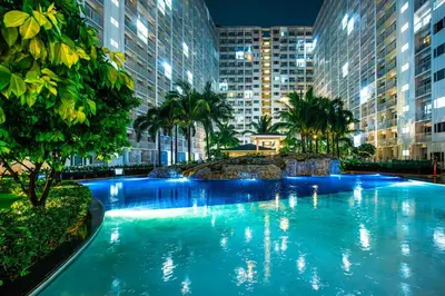 a large swimming pool in a city at night at Relaxing Hotel Apartment Stay : Near MOA & Airport in Manila