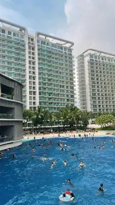 a group of people swimming in a large swimming pool with buildings at RTO Staycation in Manila