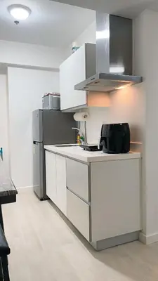 a kitchen with white cabinets and a refrigerator at RTO Staycation in Manila