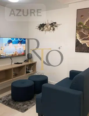 a living room with a tv and two blue chairs at RTO Staycation in Manila