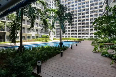 a large apartment building with a pool and palm trees at Modern Industrial 1 BR | Condo | MOA Shore 3 NAIA in Manila