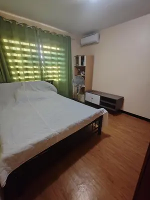 a bedroom with a bed and a window with a fan at David home in Manila