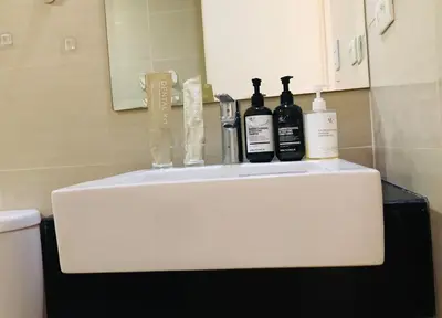 a white sink with bottles on it in a bathroom at Haven in Manila Venice 1BR with balcony near BGC in Manila