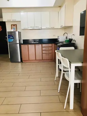 a kitchen with a table and chairs and a refrigerator at Haven in Manila Venice 1BR with balcony near BGC in Manila