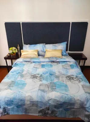 a bed with a blue comforter and two tables at Big NEW 1 Bedroom corner unit with Balconies - FREE Sauna Pool Gym View of Skyline, Manila Bay, Sunset in Manila
