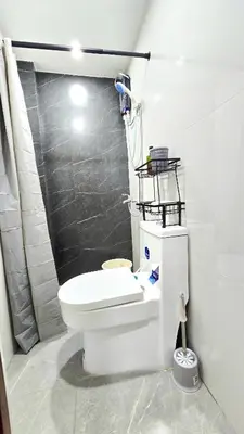 a bathroom with a white toilet and a shower at Studio Units near Airport by Jade Studio Apartments in Manila