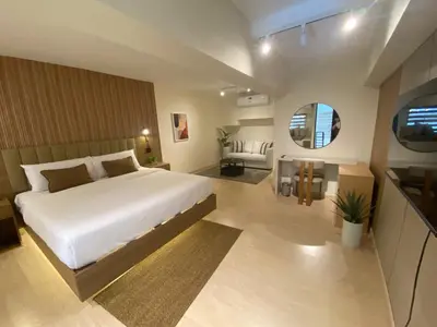 a bedroom with a large bed and a living room at EDSA Heights Penthouse unit 3402 AMA Tower Residences in Manila
