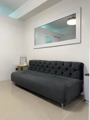 a black couch in a white room with a mirror at Staycation By ABBYBI in Manila