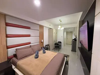 a bedroom with a bed and a flat screen tv at Staycation By ABBYBI in Manila