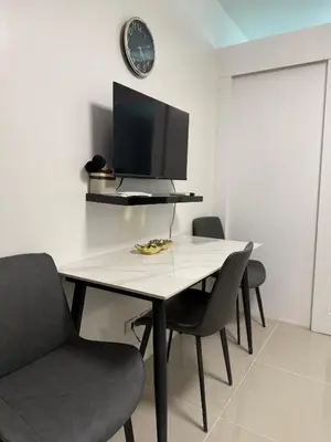 a dining room with a table with chairs and a tv at Staycation By ABBYBI in Manila