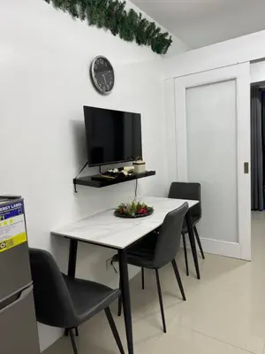 a dining room with a table and chairs and a tv at Staycation By ABBYBI in Manila