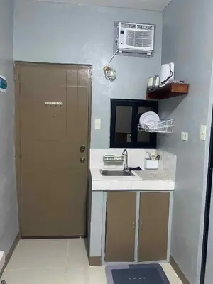 a small kitchen with a sink and a door at Airport Transient Pasay in Manila