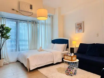a bedroom with a bed and a blue couch at The Serene Studio by Kozy Mood in Manila