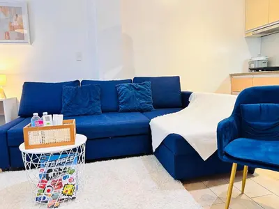 a blue couch and two chairs in a living room at The Serene Studio by Kozy Mood in Manila