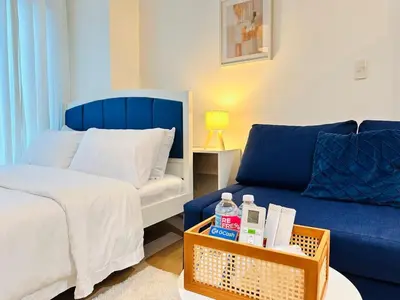 a bedroom with a bed and a blue couch at The Serene Studio by Kozy Mood in Manila