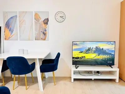 a living room with a tv and a table with chairs at The Serene Studio by Kozy Mood in Manila