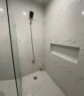 a bathroom with a shower with white marble walls at 4 Bedroom House for 5-6 guests in Manila