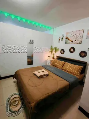a bedroom with a large bed with a green light at Staycation at Brgy Cupang in Manila