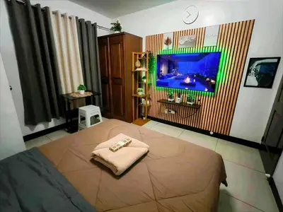 a bedroom with a bed with a tv on the wall at Staycation at Brgy Cupang in Manila